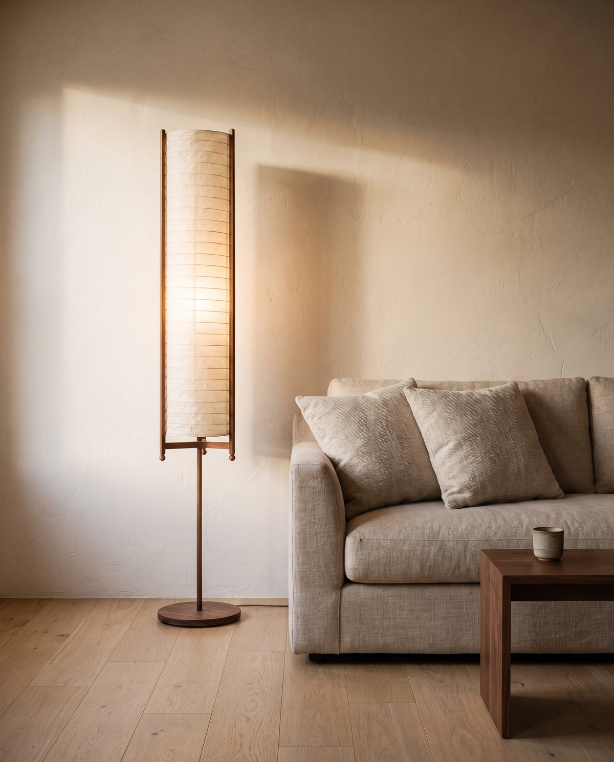 Paper floor lamp glowing beside a linen sofa in a Japandi living room